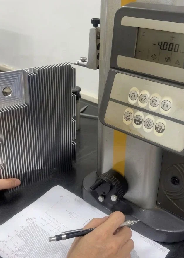 Precision height gauge inspecting step dimensions and parallelism on a CNC machined aluminum heat sink component according to drawing specifications.